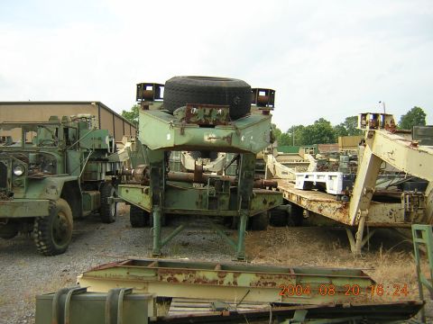 1984 Chevrolet Blazer - A collection of military vehicles and trailers are parked outdoors under a cloudy sky.
