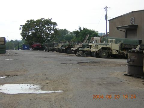 1984 Chevrolet Blazer - A line of military trucks are parked in an outdoor lot next to a building.