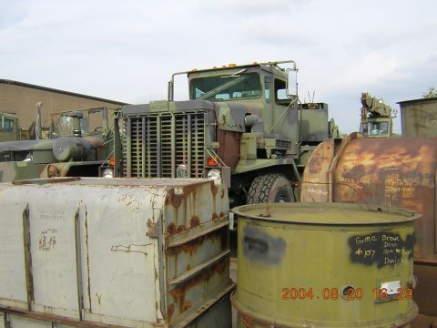 1984 Chevrolet Blazer - A military truck is parked in an outdoor lot with several large metal containers nearby.