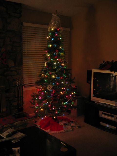 1985 Ford LTD Crown Victoria - A decorated Christmas tree stands in a living room, illuminated by colorful lights.