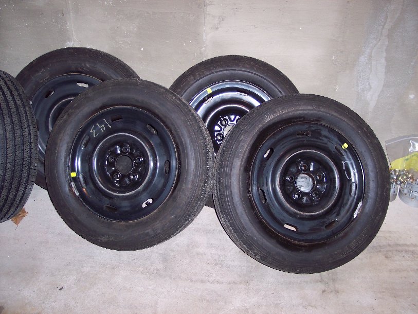 Four black spare tires with steel wheels, some marked with numbers