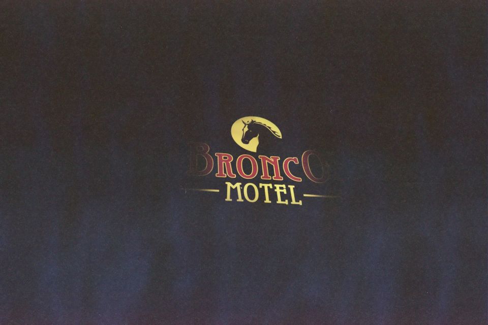 Illuminated Bronco Motel sign with a yellow horse-head logo and red lettering against dark background