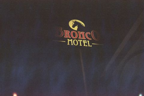 1990 Ford Bronco - Bronco Motel sign glows at night, its yellow horse-head emblem set above red Bronco lettering and yellow Motel text.