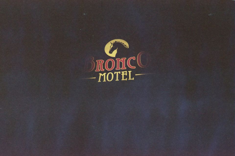 Bronco Motel sign with yellow horse-head emblem and red lettering on a dark blue background