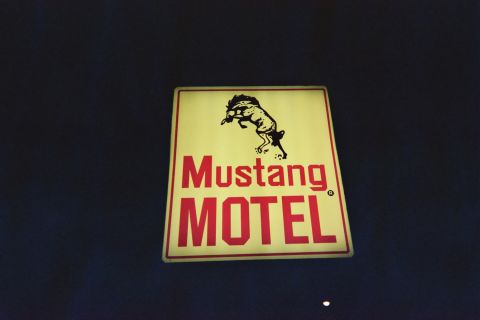 1968 Ford Mustang - A sign for the Mustang Motel displays the name and a graphic of a bucking horse against a dark background.