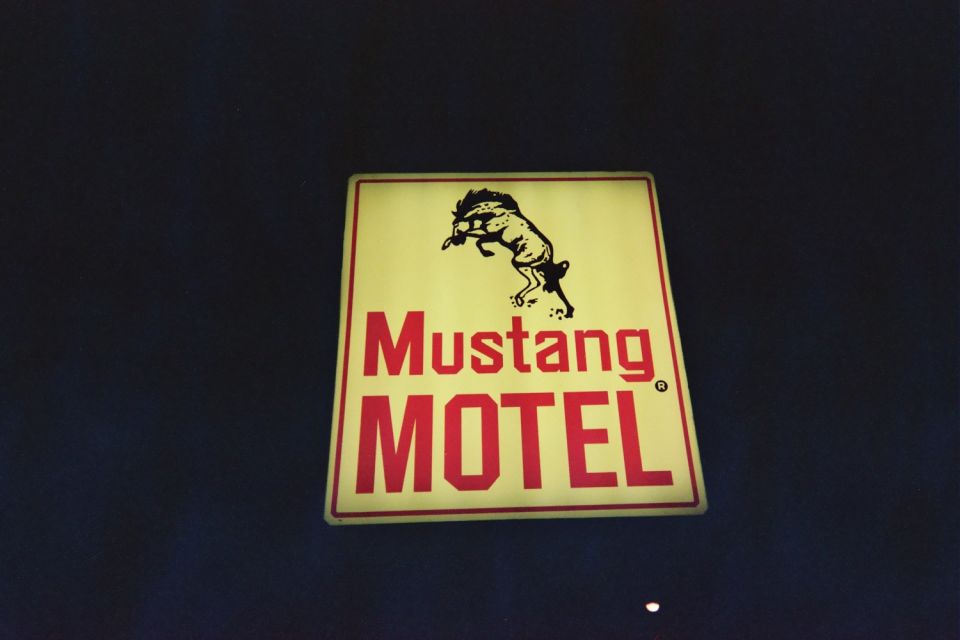 Yellow sign with red text 'Mustang MOTEL' and a black silhouette of a bucking horse