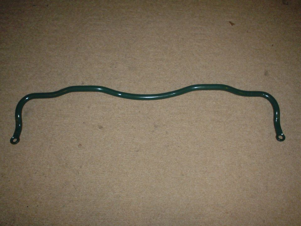 Green sway bar with wavy center and mounting holes at ends, on carpeted surface