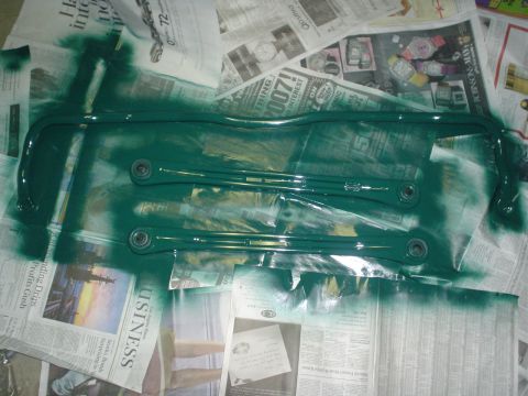 1993 Ford Taurus - Sway bars being painted green, laid out on a surface covered with newspaper.