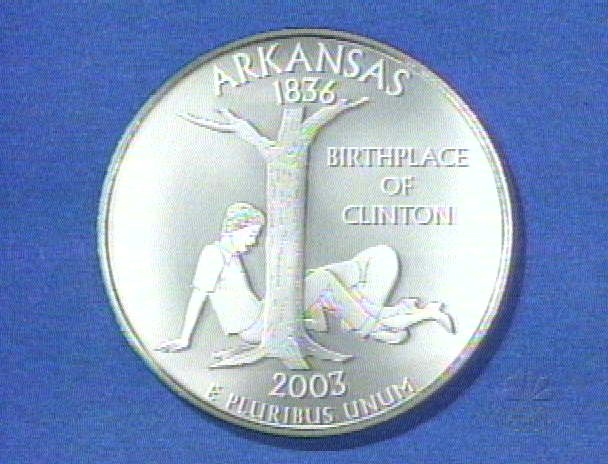 Coin with tree, two figures, and text 'ARKANSAS 1836 BIRTHPLACE OF CLINTON 2003 E PLURIBUS UNUM'