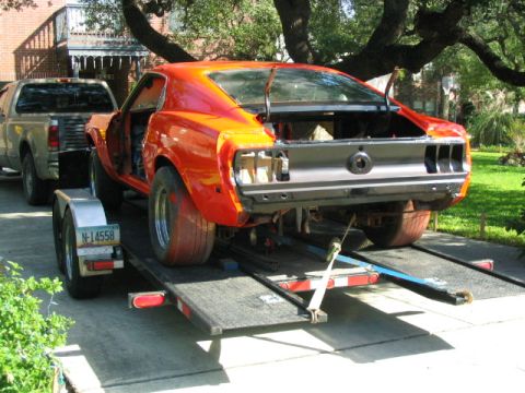 1969 Ford Mustang - Orange 1969 Ford Mustang being transported on a trailer, with a pickup truck visible.