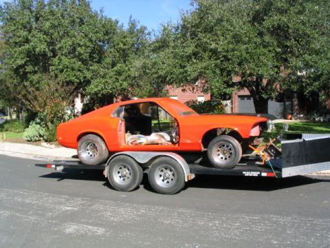 1969 Ford Mustang - Orange 1969 Ford Mustang coupe being transported on a trailer, appearing to be a project car.