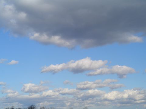 1990 Ford Bronco - The sky is filled with fluffy white and dark gray clouds against a bright blue backdrop.