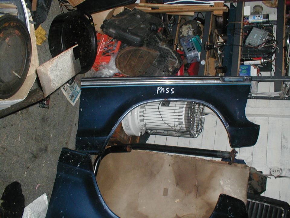 Dark blue car fender with chrome trim and 'PASS' written in white marker. A fan is visible inside the wheel well