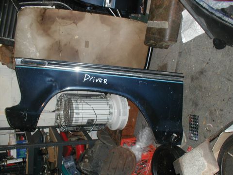 1979 Ford Bronco - A detached vehicle fender is shown in a cluttered garage setting.
