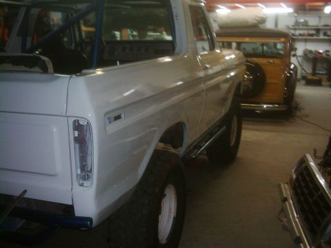 1978 Ford Bronco - A white SUV is parked in a garage, with a wood-paneled wagon visible in the background.