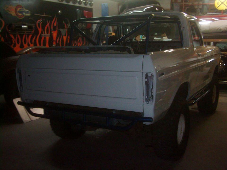 White 1978 Ford Bronco rear view, unfinished body, roll cage, aftermarket bumper