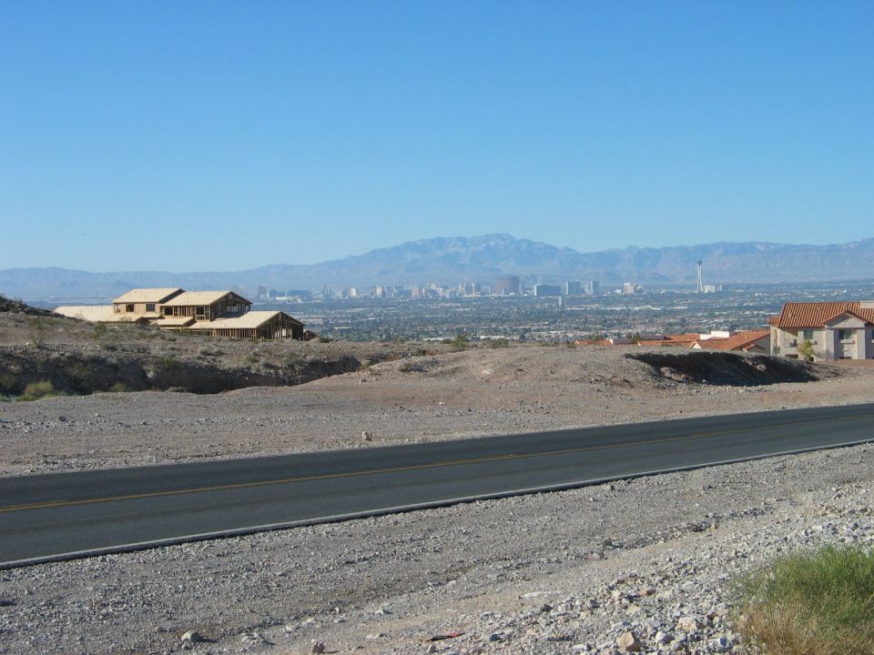View of Las Vegas skyline from a distance, with mountains in the background and houses in the foreground