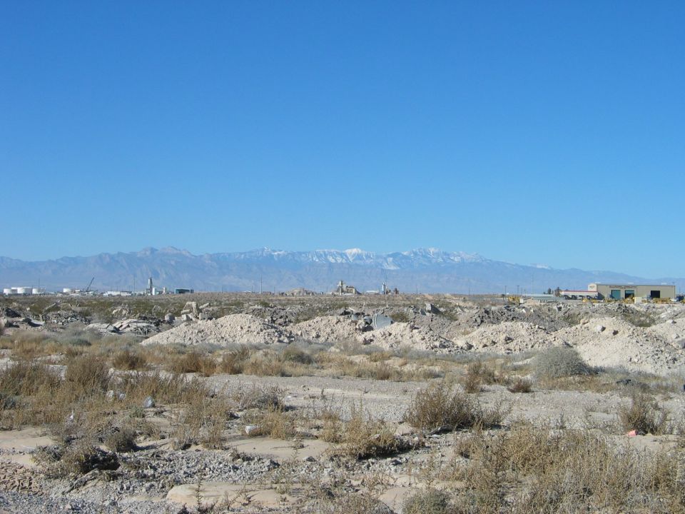 Desert landscape with mountains and industrial buildings under a clear blue sky