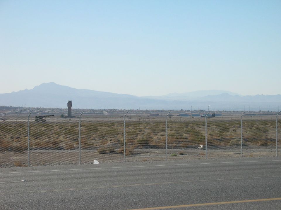 Airport control tower and distant aircraft on a clear day, with mountains in the background