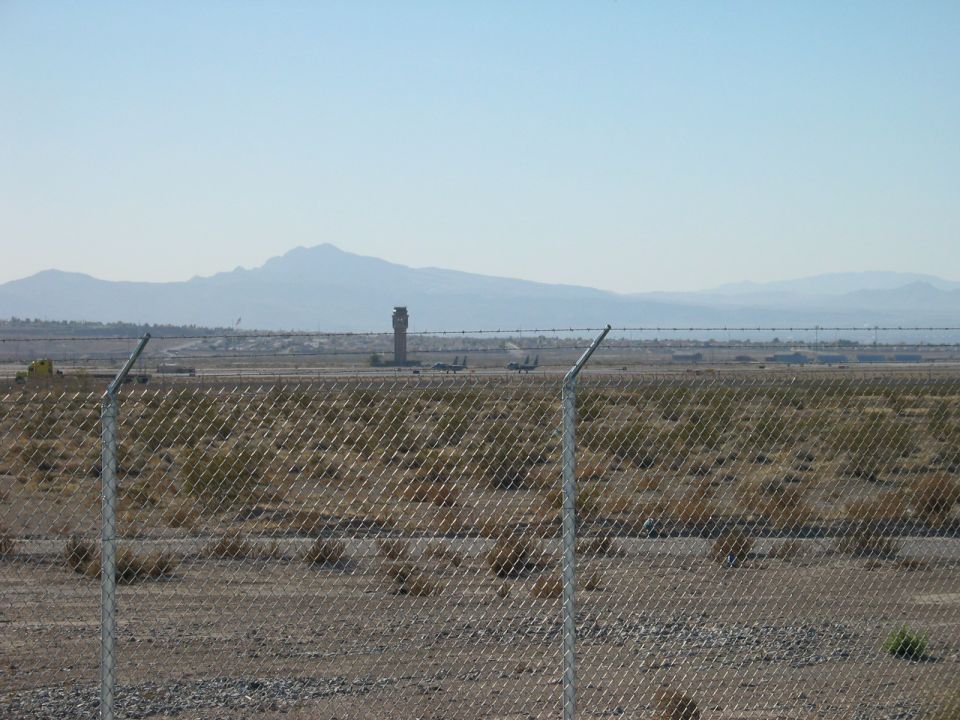 Airport with control tower, planes on tarmac, and mountains in distance