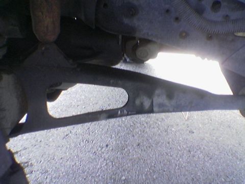 1990 Ford Bronco - Close-up view of the undercarriage of a vehicle, focusing on suspension and drivetrain components.