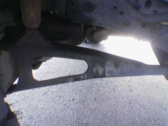 Underside of a vehicle showing suspension parts and a driveshaft