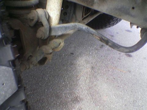 1990 Ford Bronco - A close-up view of a vehicle's suspension system and tire, with visible wear and tear on asphalt.