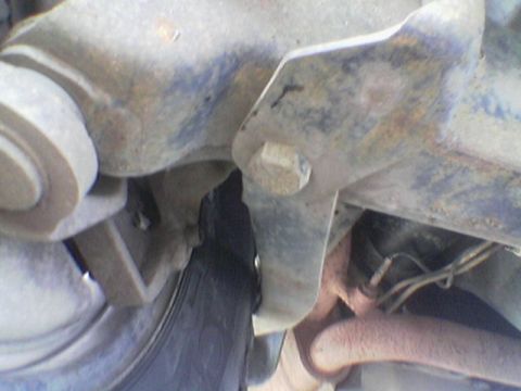 1990 Ford Bronco - Close-up of the undercarriage reveals suspension components and a tire, with visible rust and a prominent bolt.