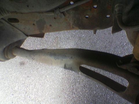 1990 Ford Bronco - The photo shows the rusty undercarriage of a vehicle, including the frame and exhaust system.