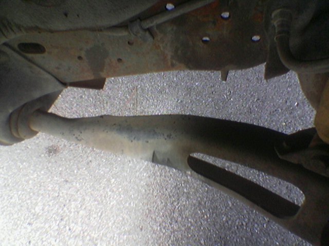 Underside of a vehicle showing rusty frame and exhaust pipe