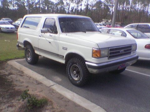 1990 Ford Bronco - This 1990 Ford Bronco is parked in a lot with other vehicles visible in the background.