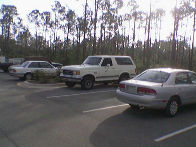 White 1990 Ford Bronco parked in a lot, viewed from the front-right