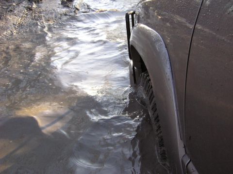 2000 Chevrolet Tahoe - Vehicle driving through a water-filled muddy track.