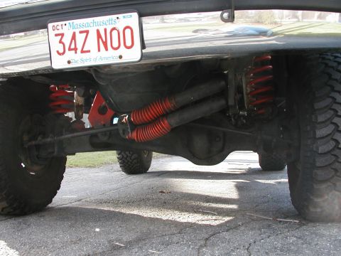 1994 Ford Bronco - Close-up view of the rear axle and suspension of a 1994 Ford Bronco, showing modified red springs and shocks.
