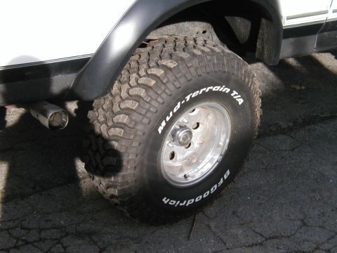 1994 Ford Bronco - Close-up of a BFGoodrich Mud-Terrain T/A tire and chrome wheel, with a visible exhaust pipe.