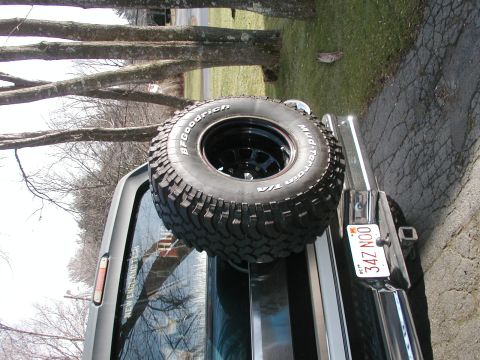 1994 Ford Bronco - Sideways-rotated rear view of a two-tone green-and-white SUV with a BFGoodrich Mud-Terrain T/A spare tire on a black steel wheel resting on…