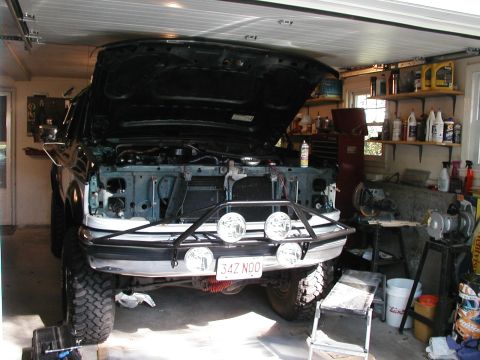1994 Ford Bronco - Front view of a 1994 Ford Bronco in a garage, hood open, with an aftermarket bumper and auxiliary lights.