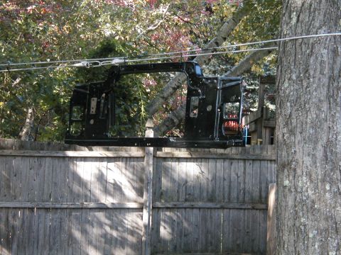1994 Ford Bronco - Vehicle frame suspended outdoors, possibly for painting or repair.