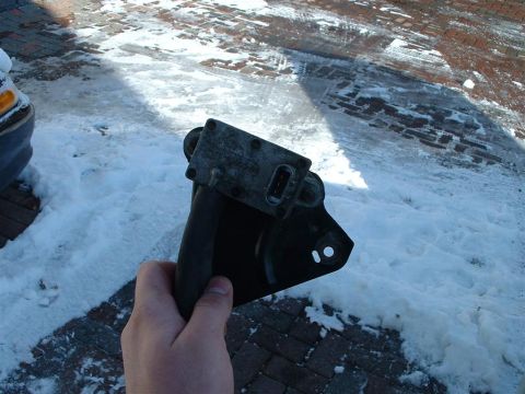 1996 Ford Crown Victoria - A car part is held up in front of a snowy, brick-paved area.