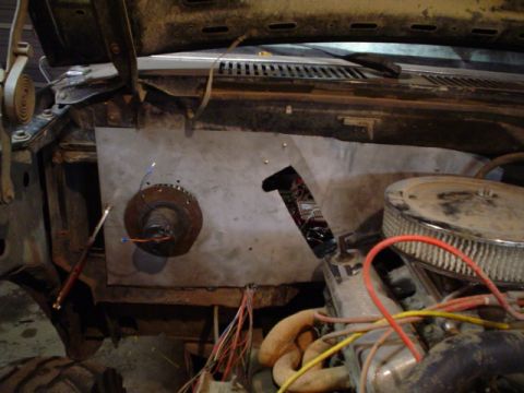 1981 Ford Bronco - Engine bay view of a stripped firewall with a bare sheet-metal patch panel riveted in place around a wiper motor, wiring harness leads hang…