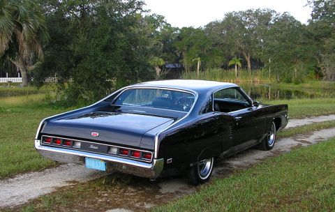 1969 Mercury Marauder - A black 1969 Mercury Marauder is parked on a dirt road with trees and a pond in the background.