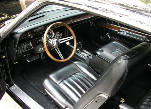 1969 Mercury Marauder - The interior of a 1969 Mercury Marauder features black leather bucket seats, a wood-rimmed steering wheel, and wood grain trim on the dashb…