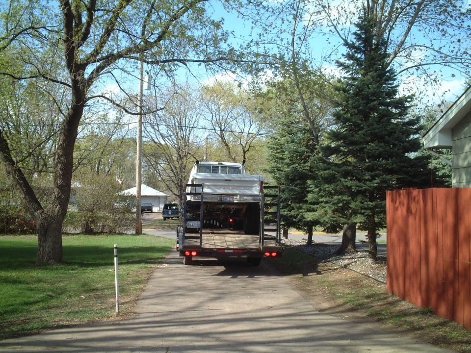 Trailer loaded with a truck bed, parked on a driveway