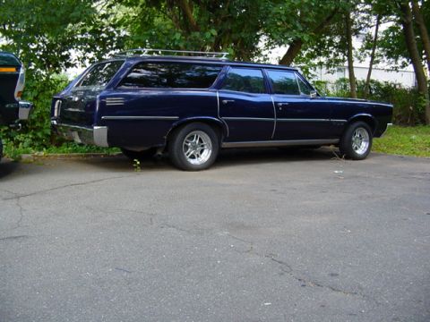 1967 Pontiac Tempest - A dark blue station wagon is parked on asphalt next to another vehicle, with trees in the background.