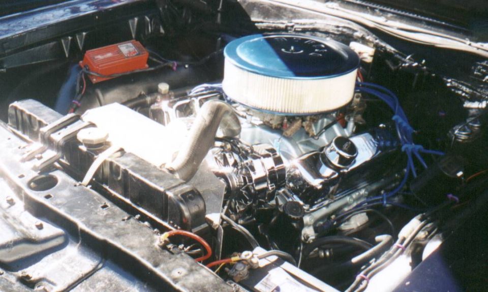 V8 engine bay with chrome air cleaner, blue plug wires, and radiator