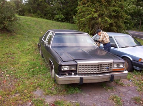 1991 Ford LTD Crown Victoria - A 1991 Ford Crown Victoria LTD is seen parked on the grass, with another vehicle beside it and a person working on the second car.