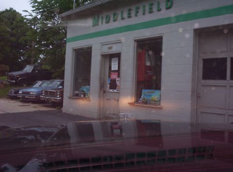 1991 Ford LTD Crown Victoria - Several older vehicles are parked outside a building with 'MIDDLEFIELD' signage. The scene appears to be a service station.