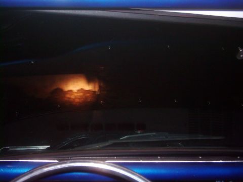 1978 Ford Bronco - The windshield reflects a fiery scene, possibly a building or a sunset, from inside the car.