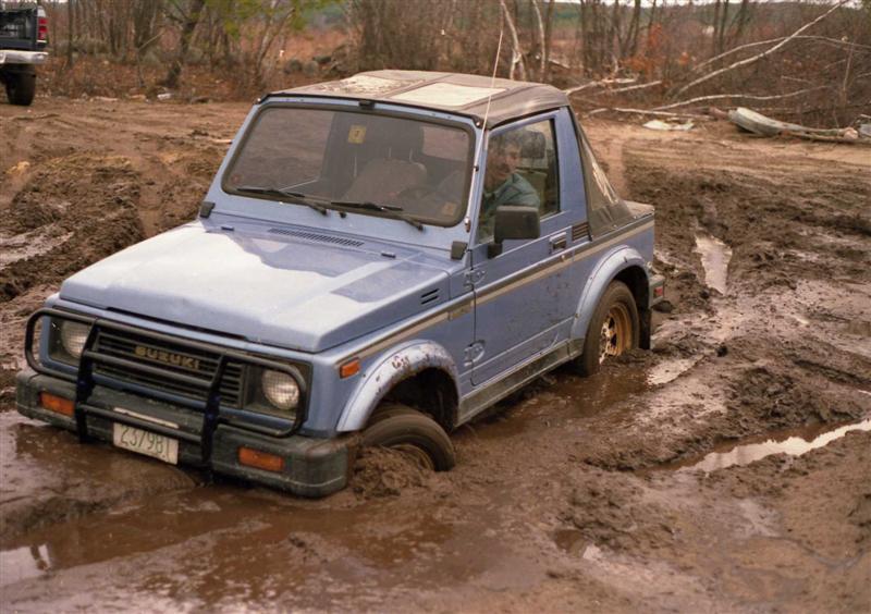 Blue Suzuki Samurai stuck in mud, front grille has 'SUZUKI' text and license plate '237981'