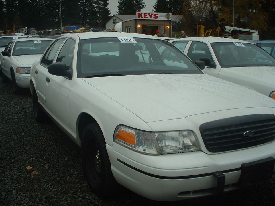 White Ford Crown Victoria with black grille and black wheels, parked in a lot